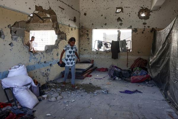 A young Palestinian woman checks the damage inside a classroom at the al-Zahra school used as a refuge by displaced Palestinians, after it was hit by an Israeli strike in the Shujaiya neighbourhood of Gaza City on August 8.